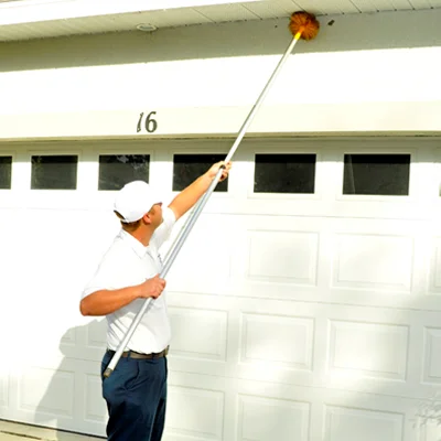 pest control technician sweeping exterior of home